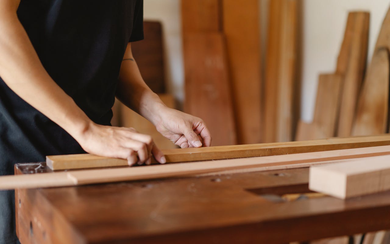 Close-up of a craftsman measuring wood in a workshop, highlighting skill and precision.
